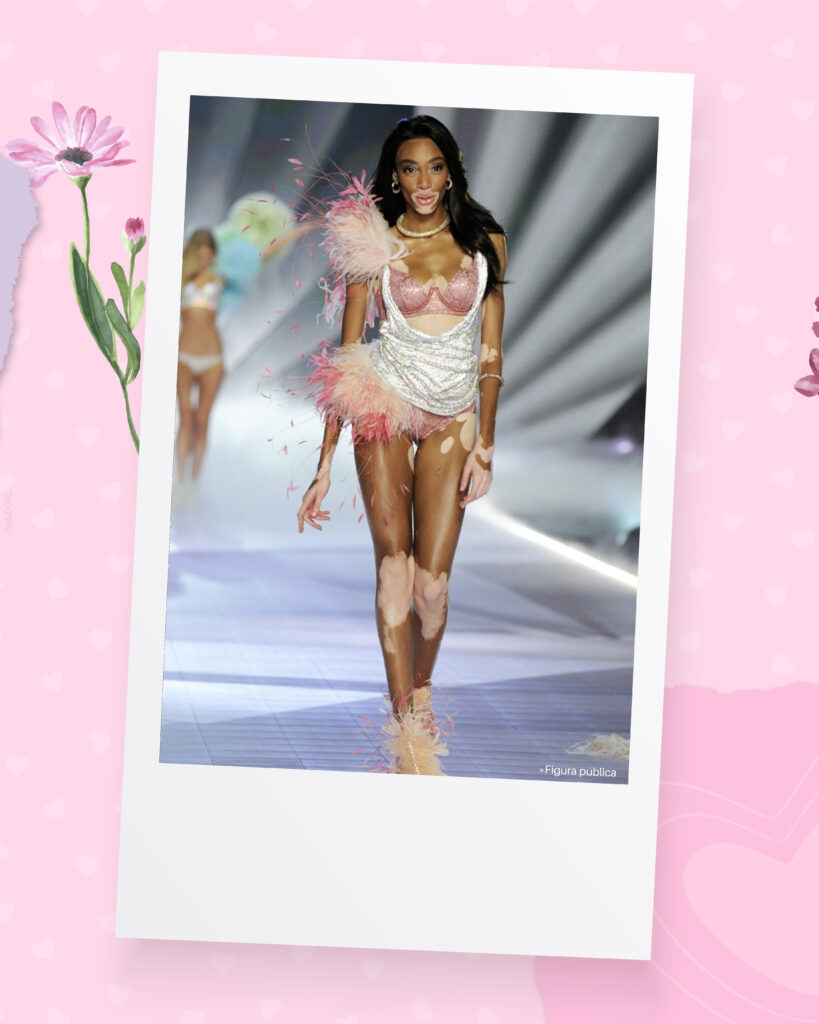 Uma das modelos inspiradoras: Winnie Harlow desfilando na passarela da Victoria 's Secret com um look branco e rosa, com plumas. 