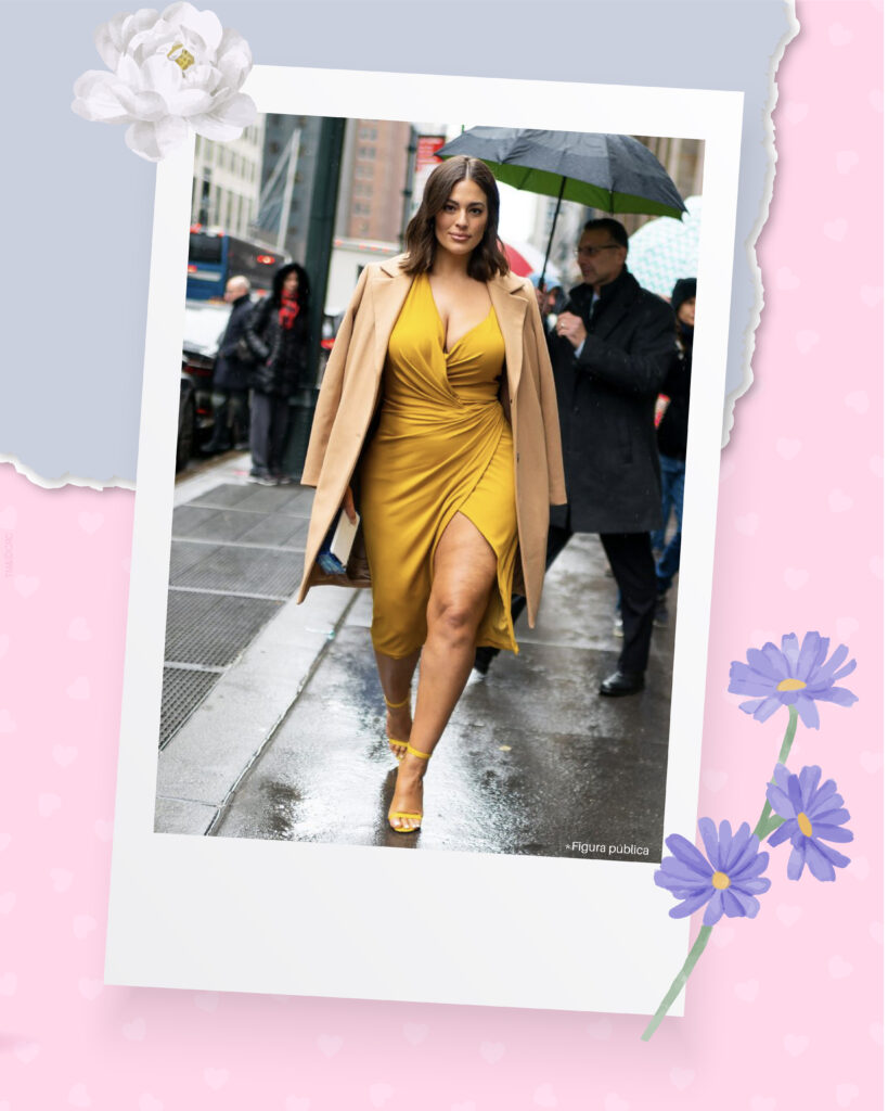 Ashley Graham andando em uma rua, com um vestido e salto amarelos, com um blazer nude. 